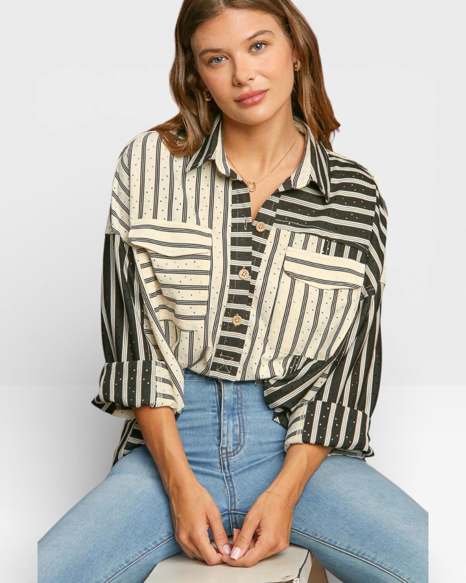Woman wearing a striped shirt and jeans sitting on a white background