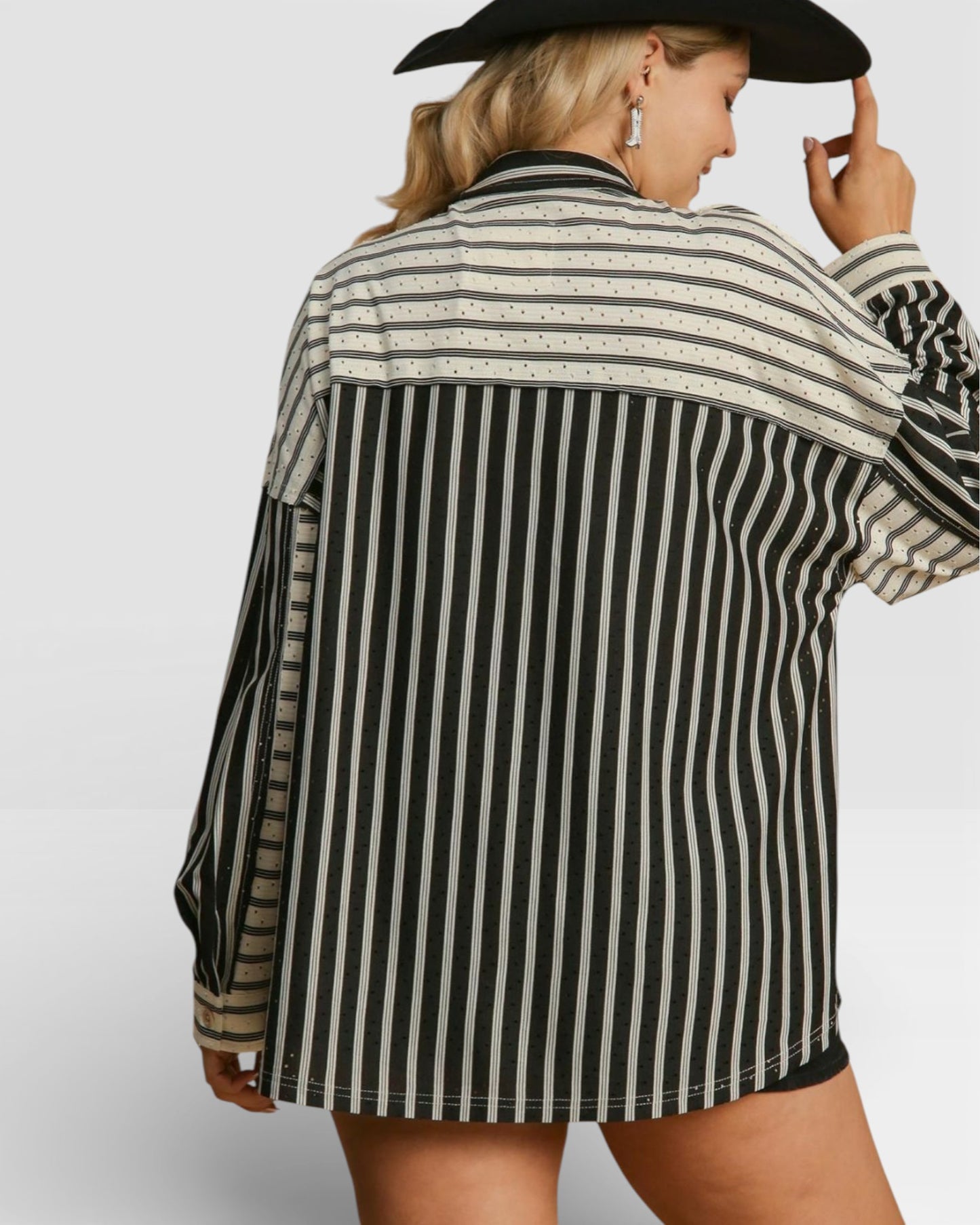 Person wearing a black and white striped shirt with a plain background