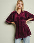 Woman wearing a burgundy velvet shirt with a plain background