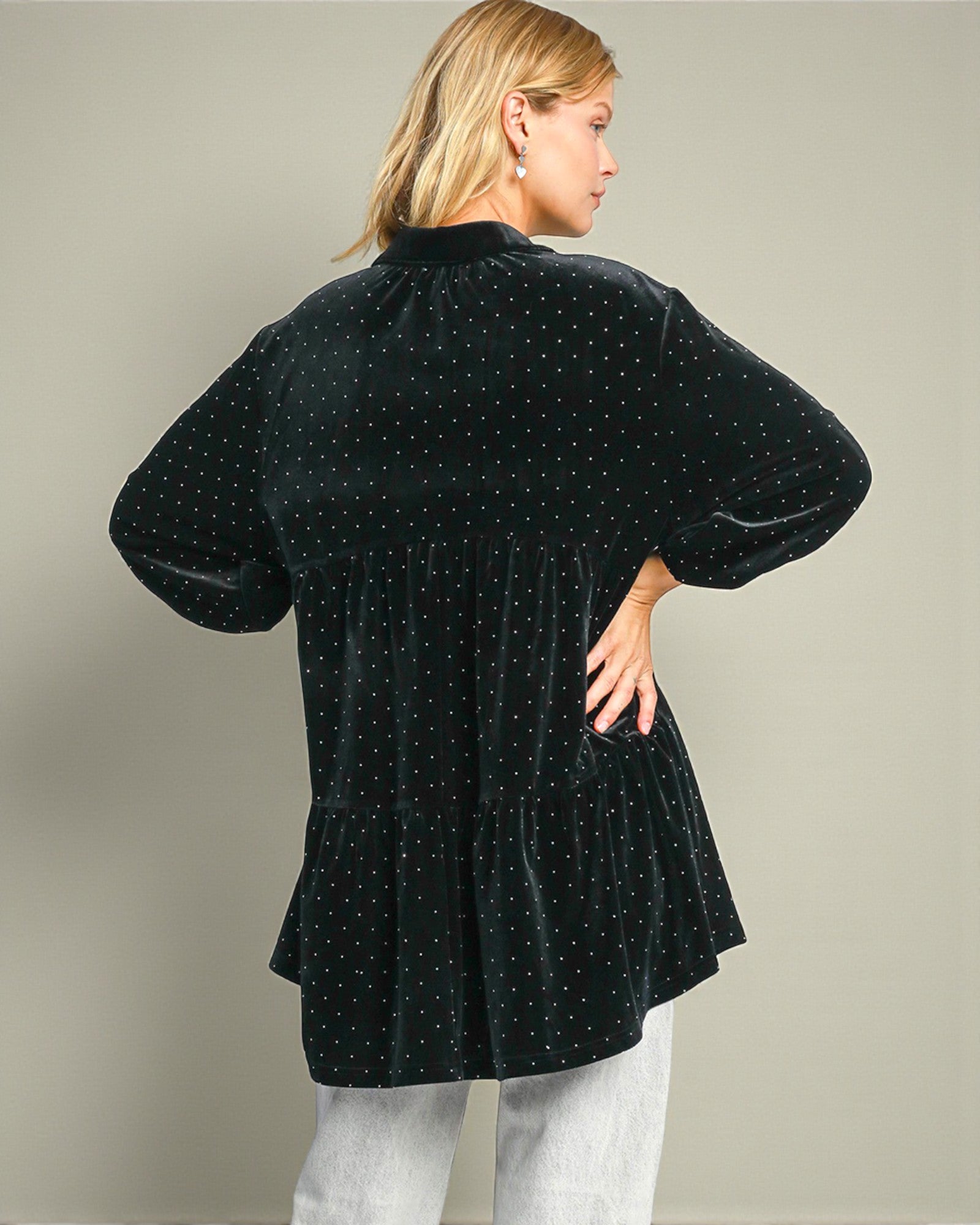 Woman wearing a black polka dot blouse against a plain background