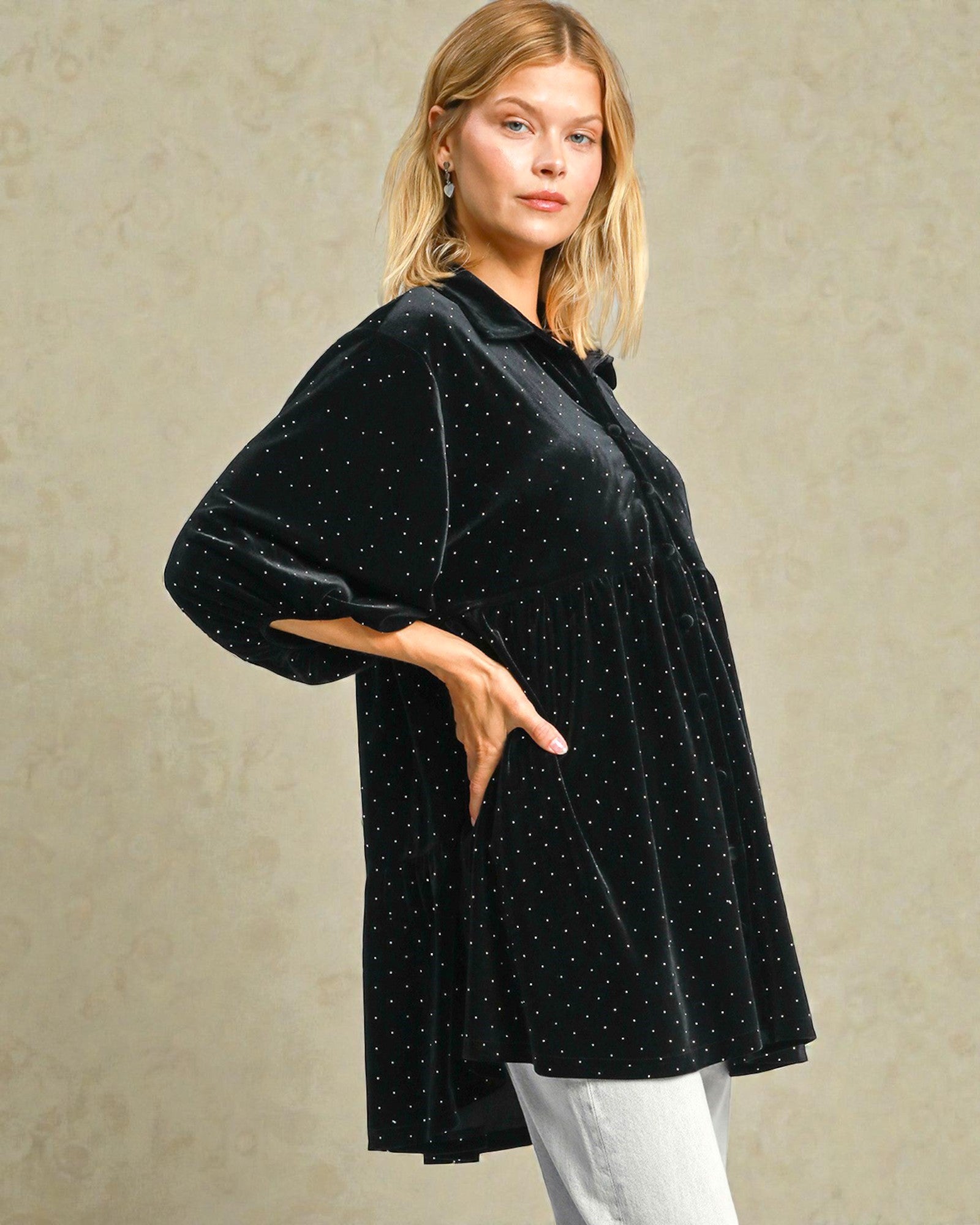 Woman wearing a black polka dot dress against a beige background
