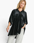 A woman modeling a black velvet button-up shirt with small white polka dots, paired with light gray jeans, against a plain white studio background.