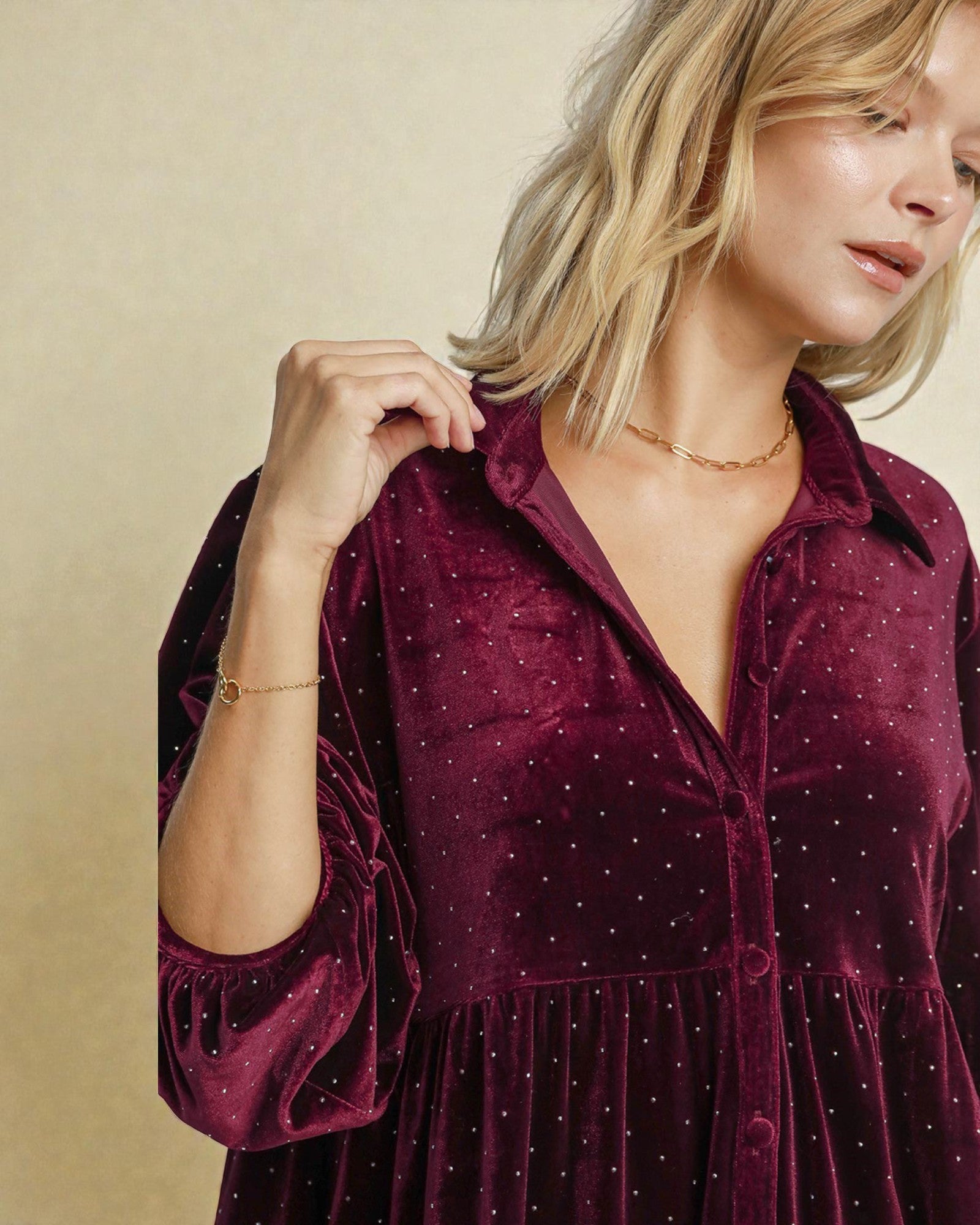 Woman wearing a burgundy velvet dress with a beige background