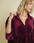 Woman wearing a burgundy velvet dress with a beige background