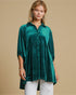 Woman wearing a green velvet blouse with a beige background