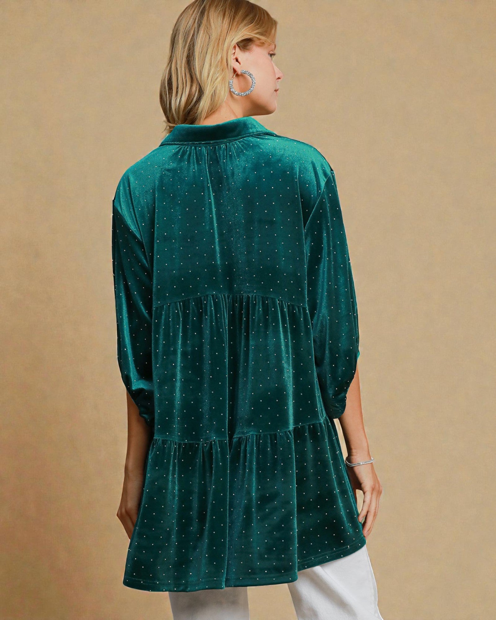 Woman wearing a green tiered dress against a beige background
