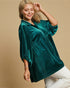 Woman wearing a green velvet blouse with white polka dots on a beige background