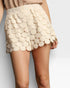 Beige scalloped shorts worn by a person on a plain background