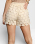 Beige scalloped shorts worn by a person on a plain background