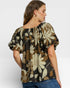 Woman wearing a floral blouse with puff sleeves on a white background