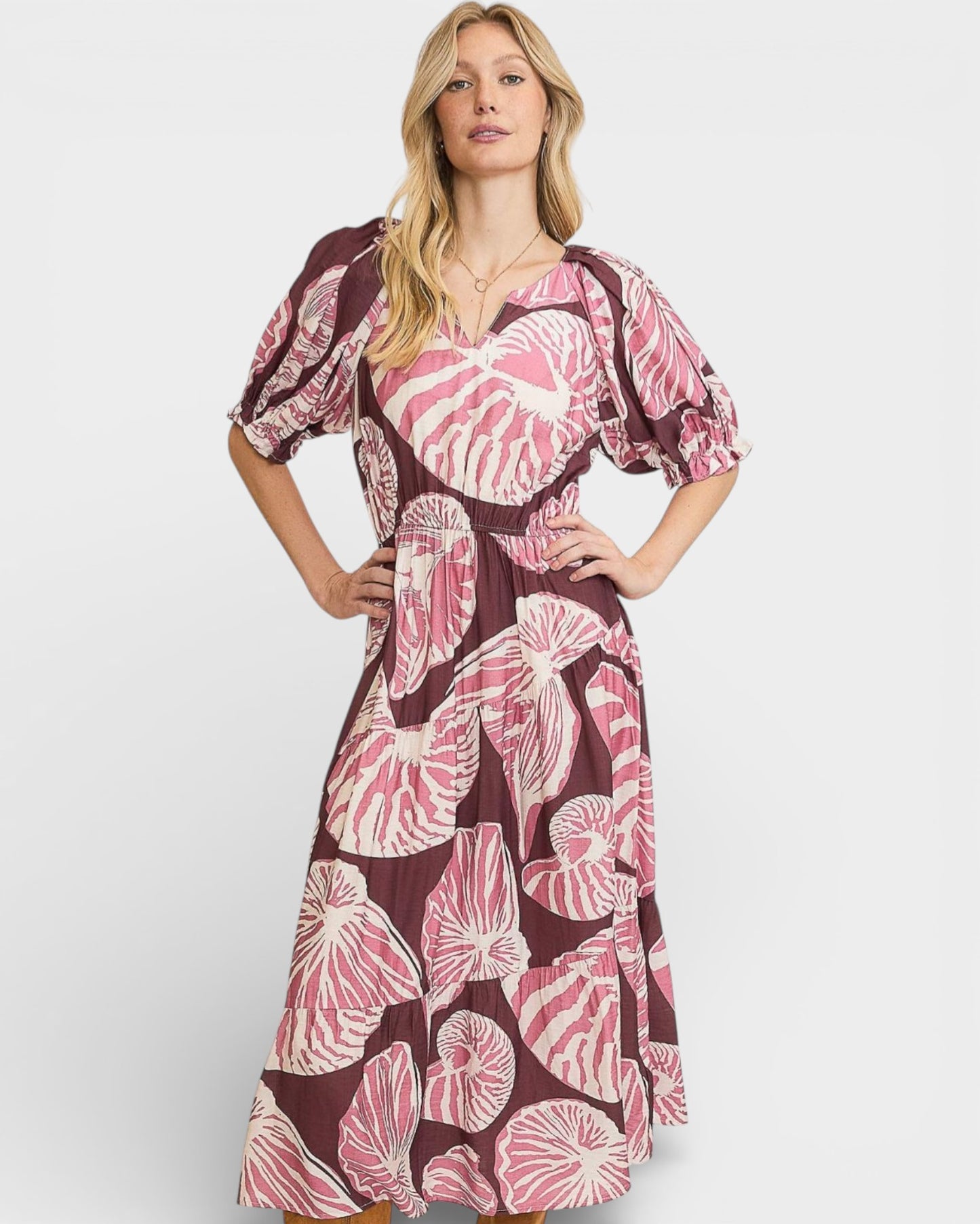 Woman wearing a pink and brown patterned dress on a white background