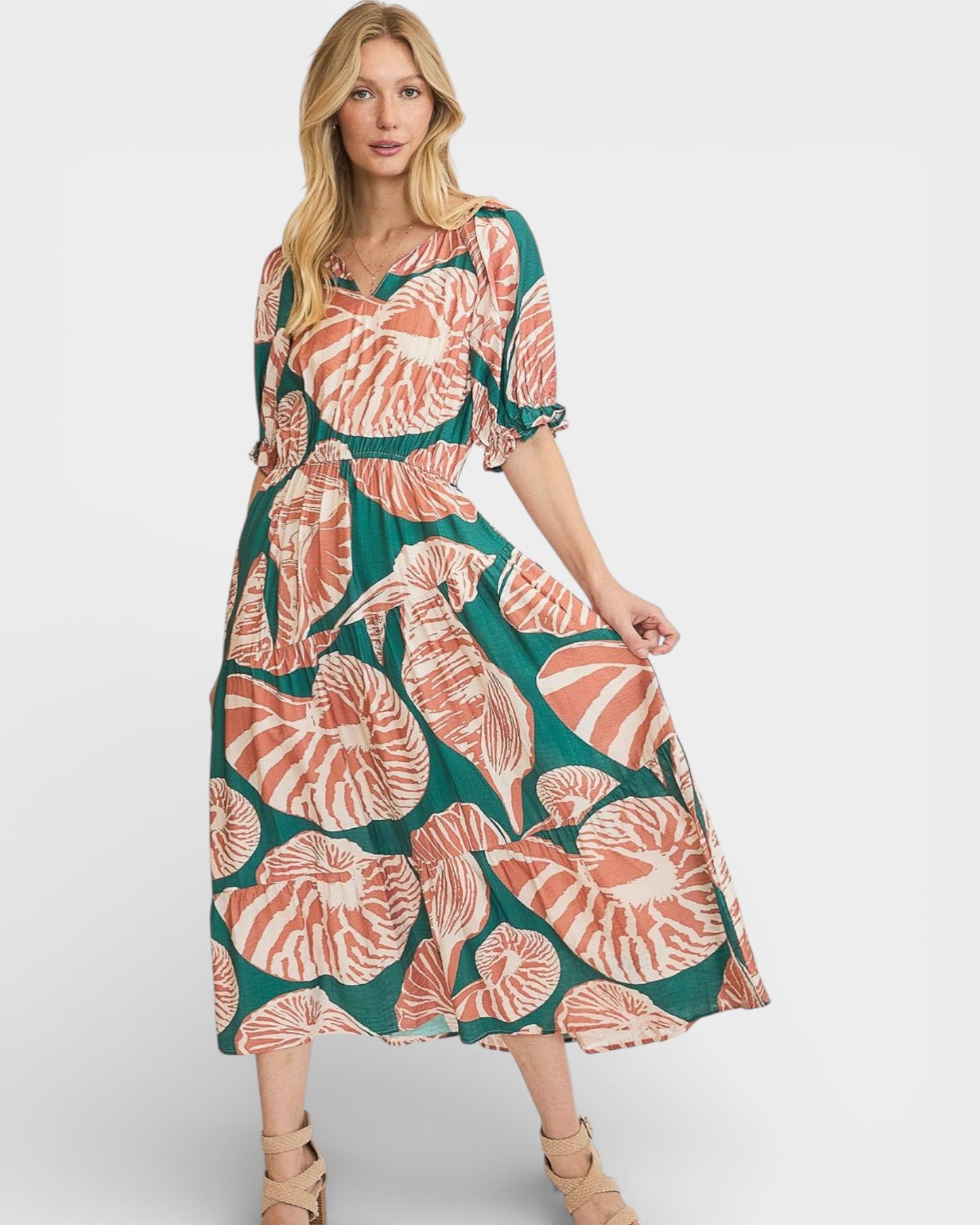 Woman wearing a floral dress with a green and pink pattern on a white background