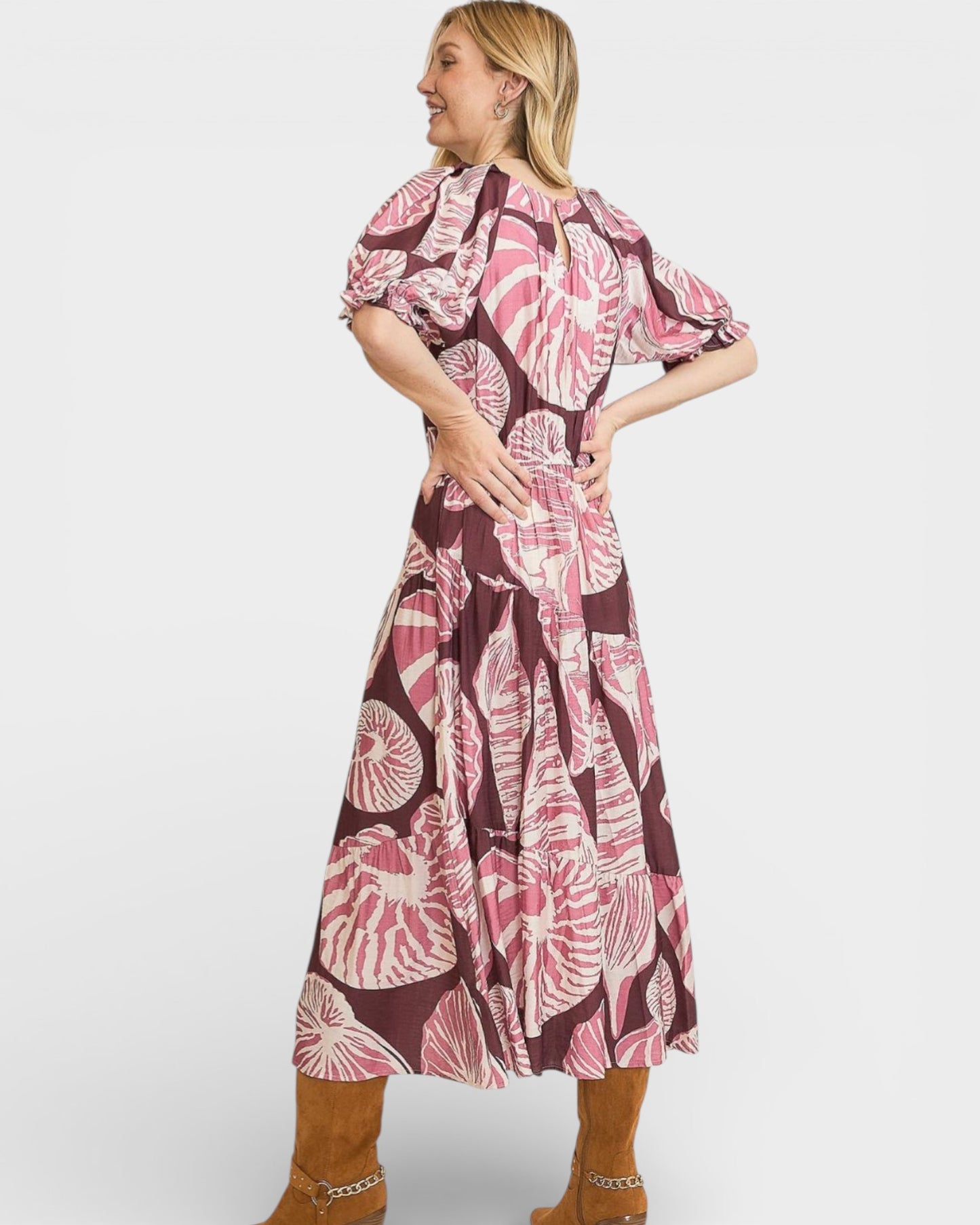 Woman wearing a pink and brown floral dress on a white background