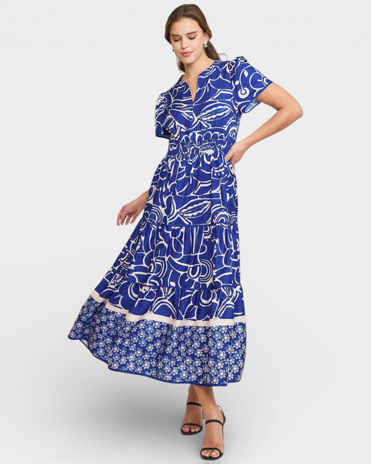 Woman wearing a blue dress with white patterns on a light gray background