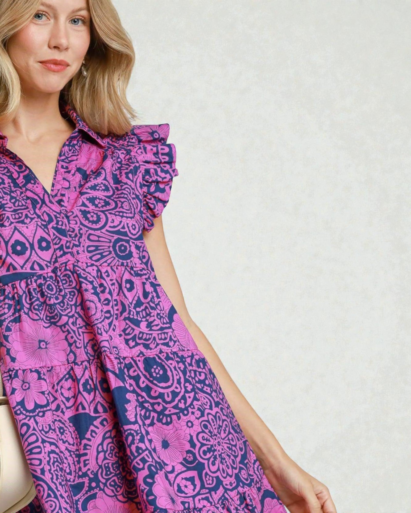 Woman wearing a pink and purple patterned dress against a white background