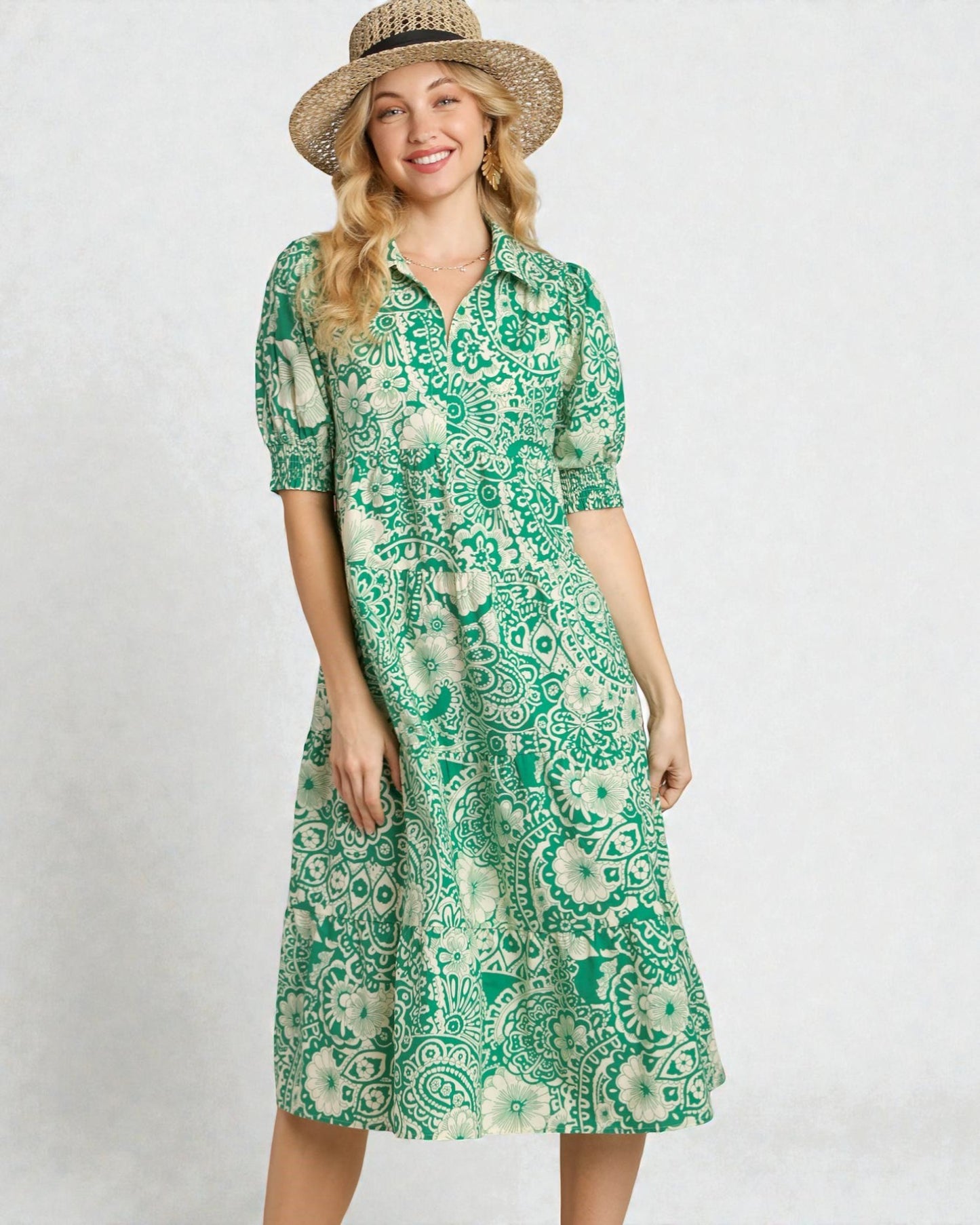 Woman wearing a green patterned dress and straw hat on a white background