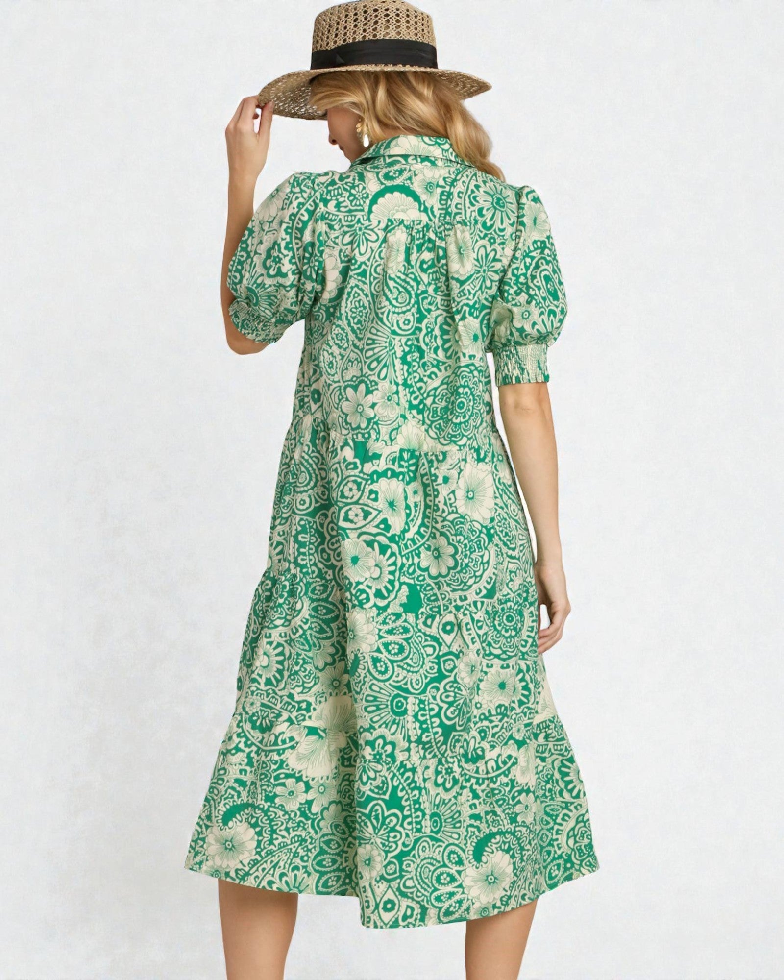 Woman wearing a green patterned dress and straw hat on a white background