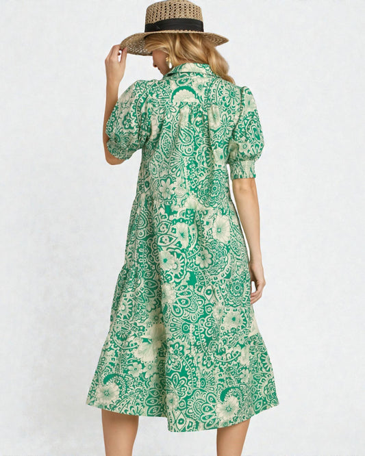 Woman wearing a green patterned dress and straw hat on a white background