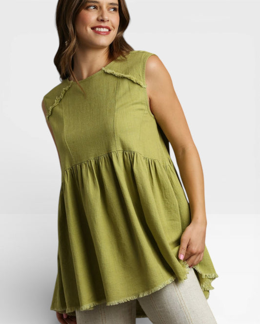 Woman wearing a green sleeveless top with ruffled details on a white background