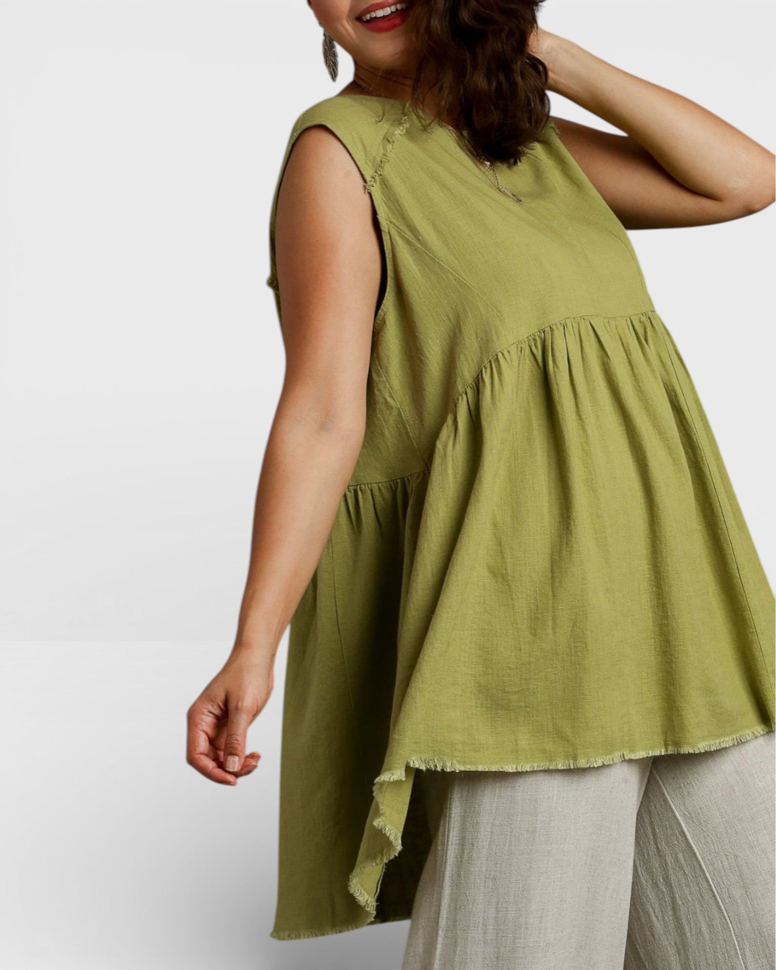 Woman wearing a green sleeveless top with a plain background