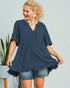 Woman wearing a navy blue dress with denim shorts against a light gray background