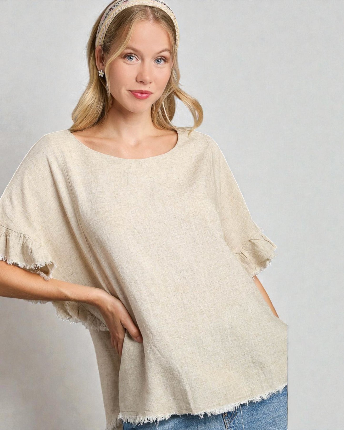 Woman wearing a beige poncho against a plain background