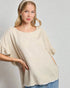 Woman wearing a beige poncho against a plain background