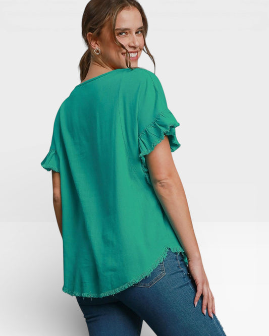 Woman wearing a green blouse with ruffled sleeves on a white background
