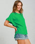 Woman wearing a green blouse and denim shorts on a plain background