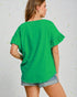 Woman wearing a green blouse with ruffled sleeves against a light background