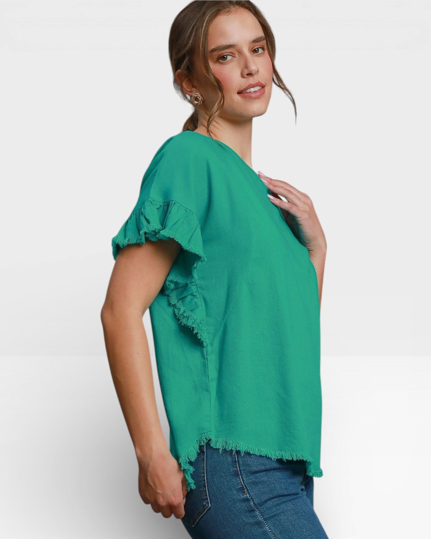 Woman wearing a green blouse with ruffled sleeves on a white background