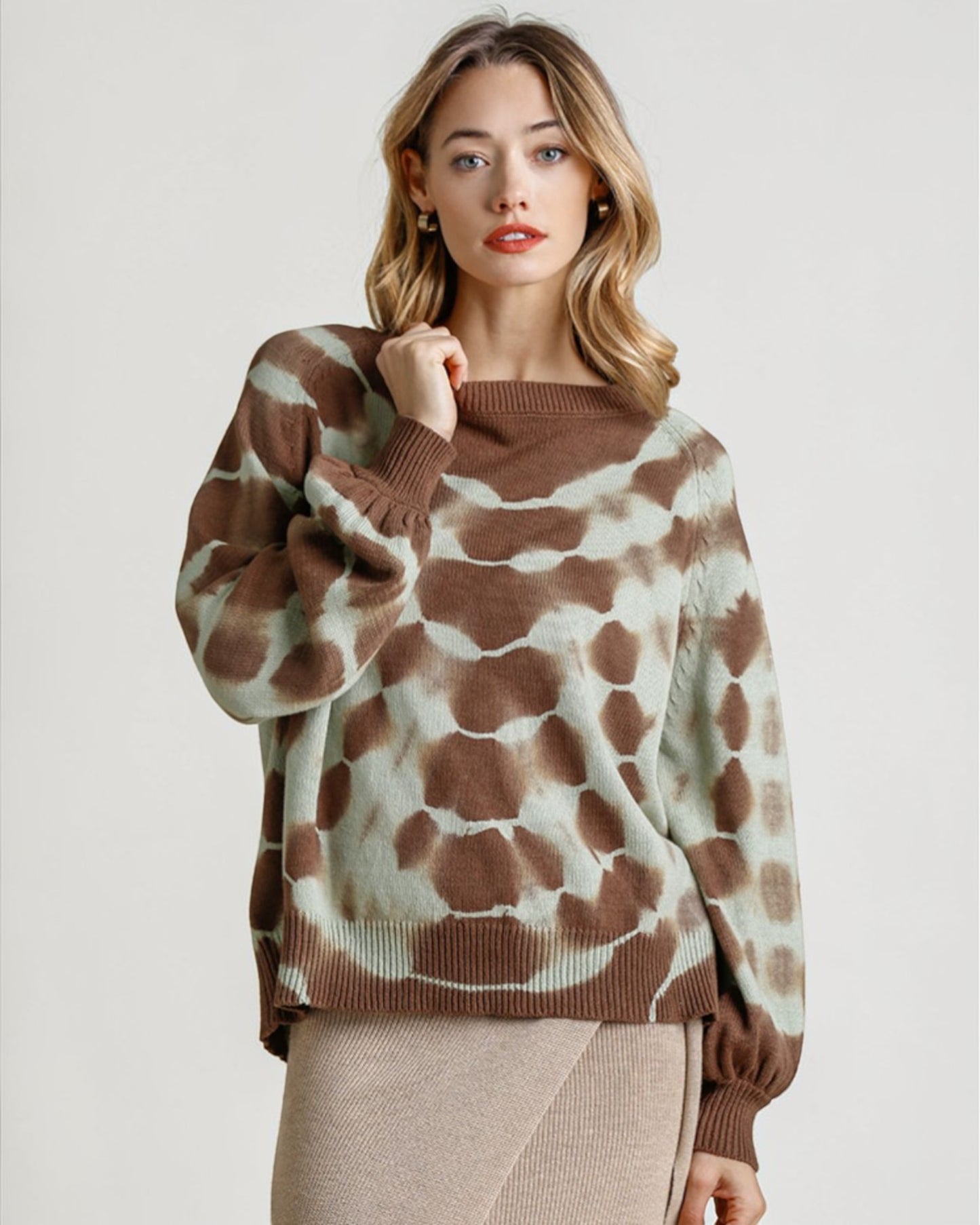 Woman wearing a brown and beige patterned sweater on a plain background