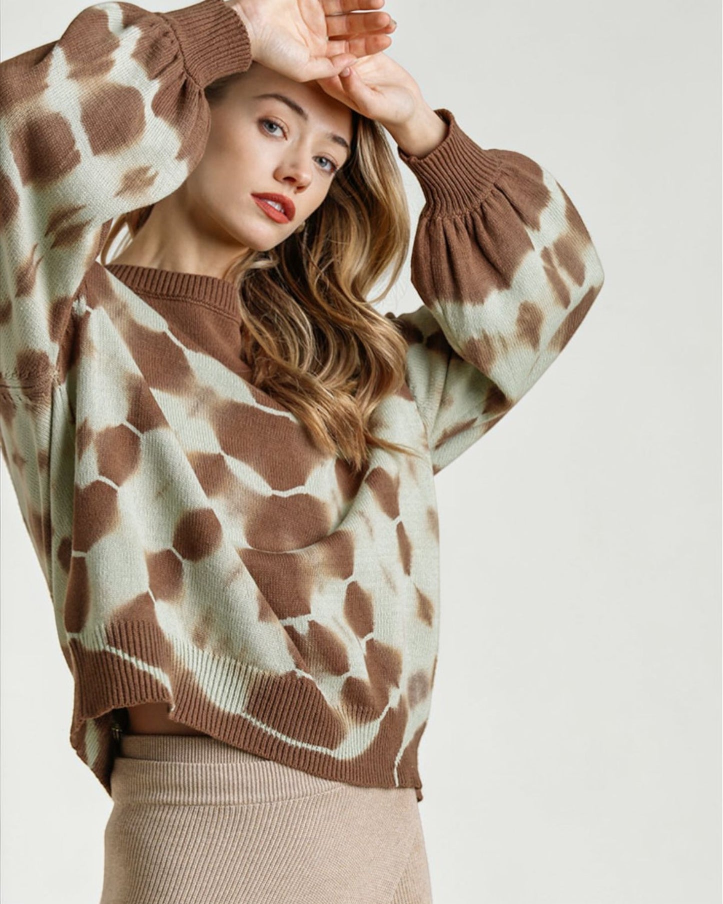 Woman wearing a giraffe patterned sweater on a plain background