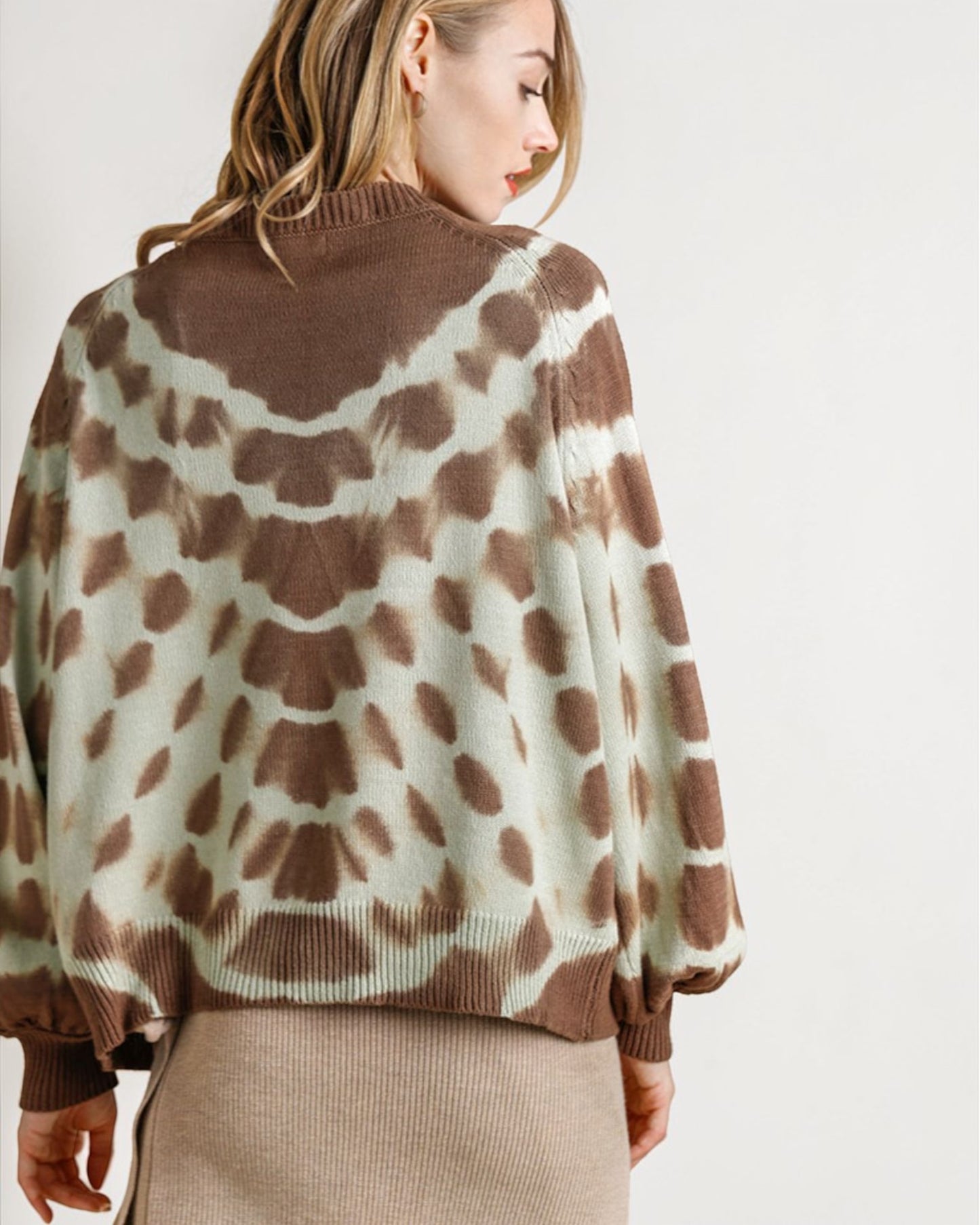 Person wearing a brown and white patterned sweater on a plain background