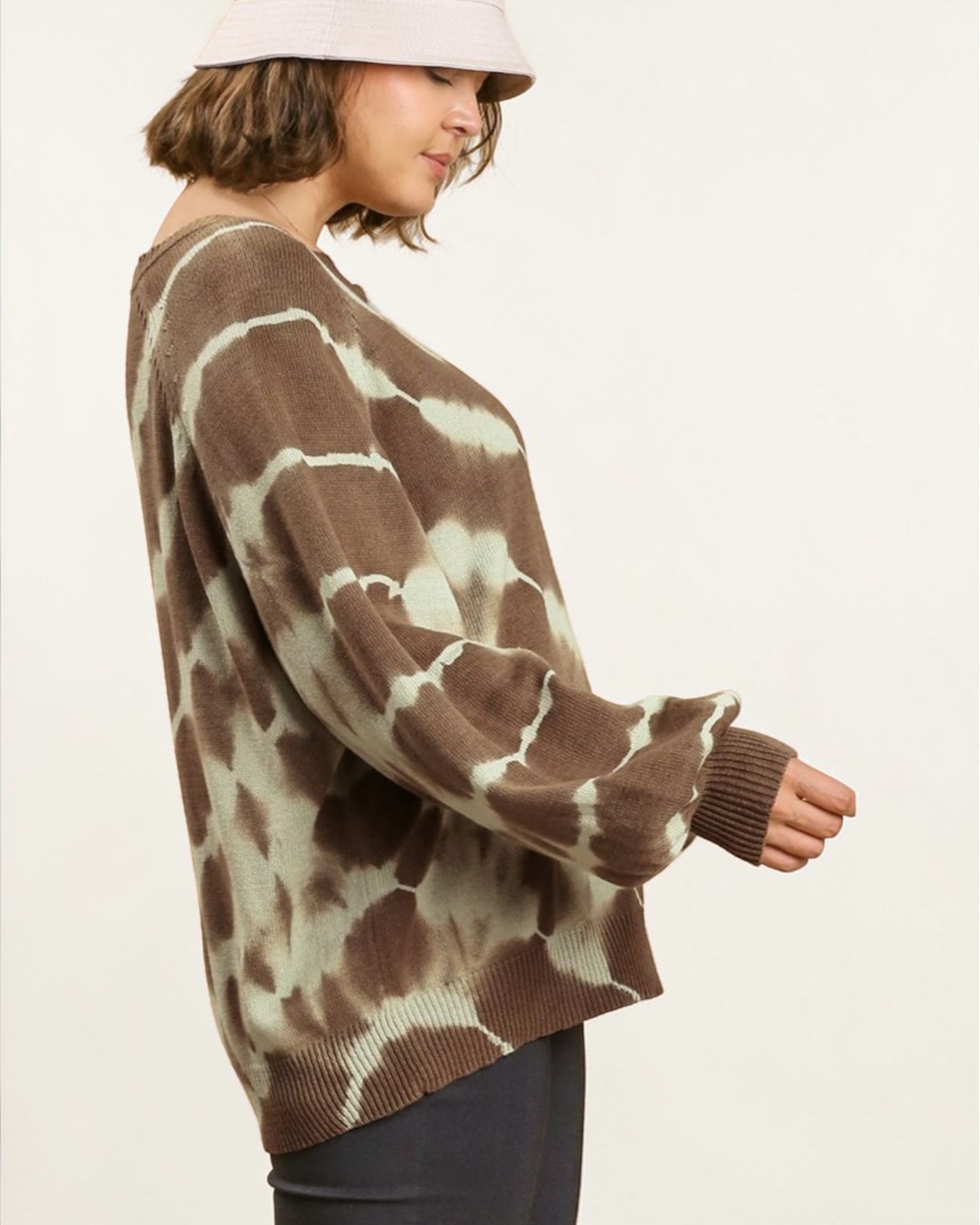 Person wearing a brown and white tie-dye sweater on a plain background