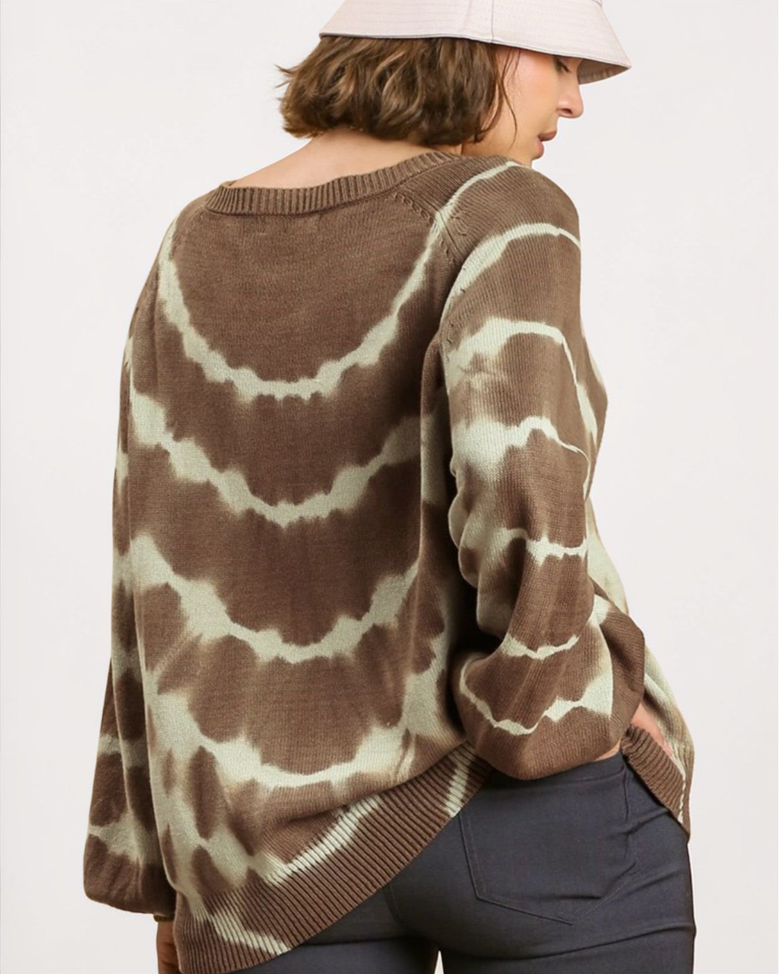 Person wearing a brown and white tie-dye sweater on a plain background