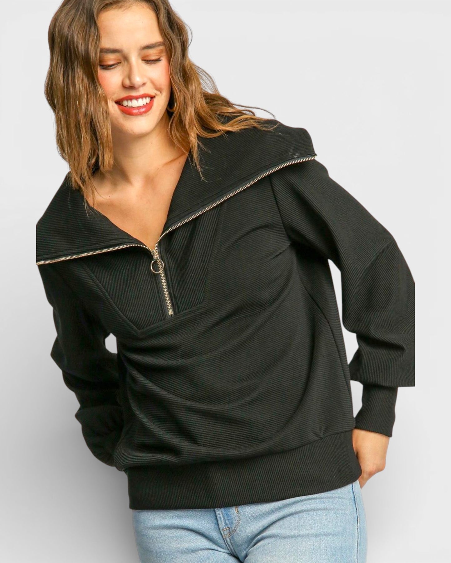 Woman wearing a black pullover with a zipper on a light gray background