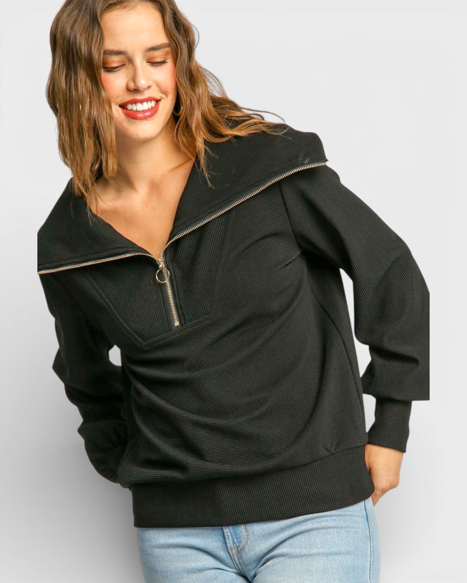 Woman wearing a black pullover with a zipper on a light gray background