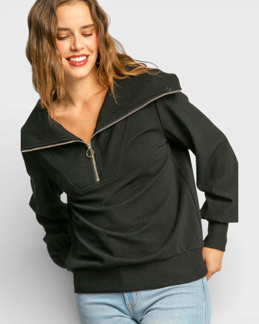 Woman wearing a black pullover with a zipper on a light gray background