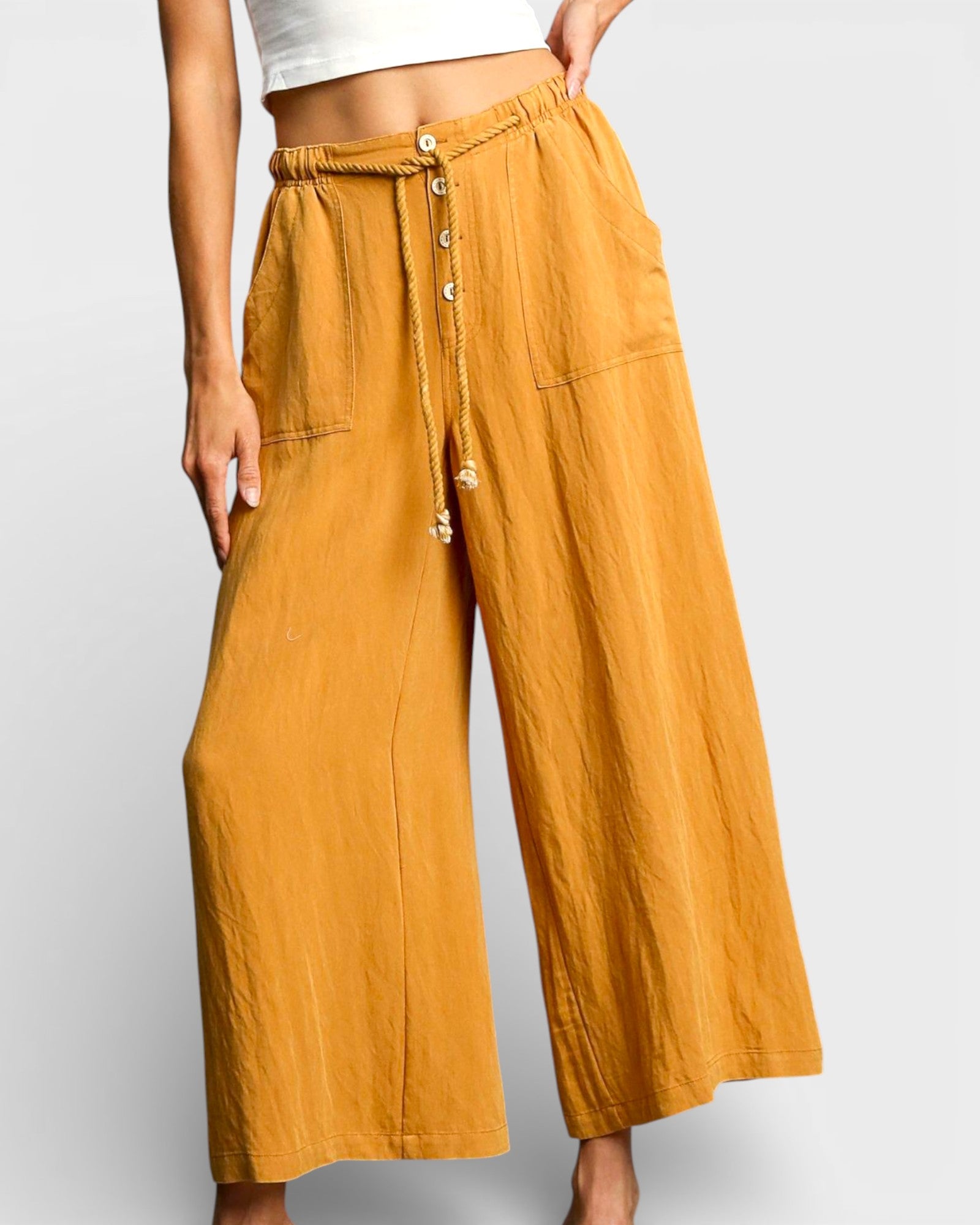 Mustard yellow wide-leg pants with button details on a plain background