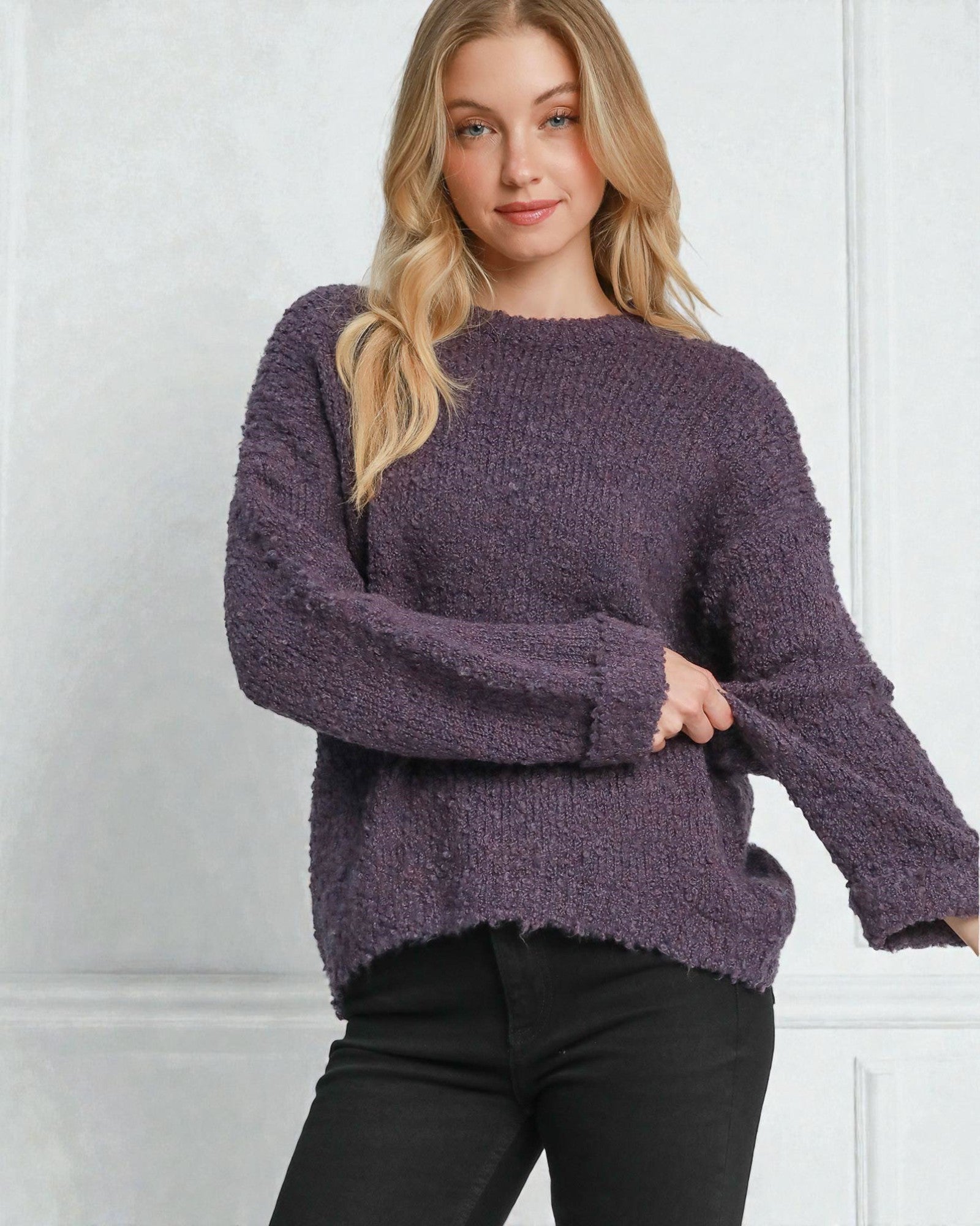 Woman wearing a purple sweater against a white wall