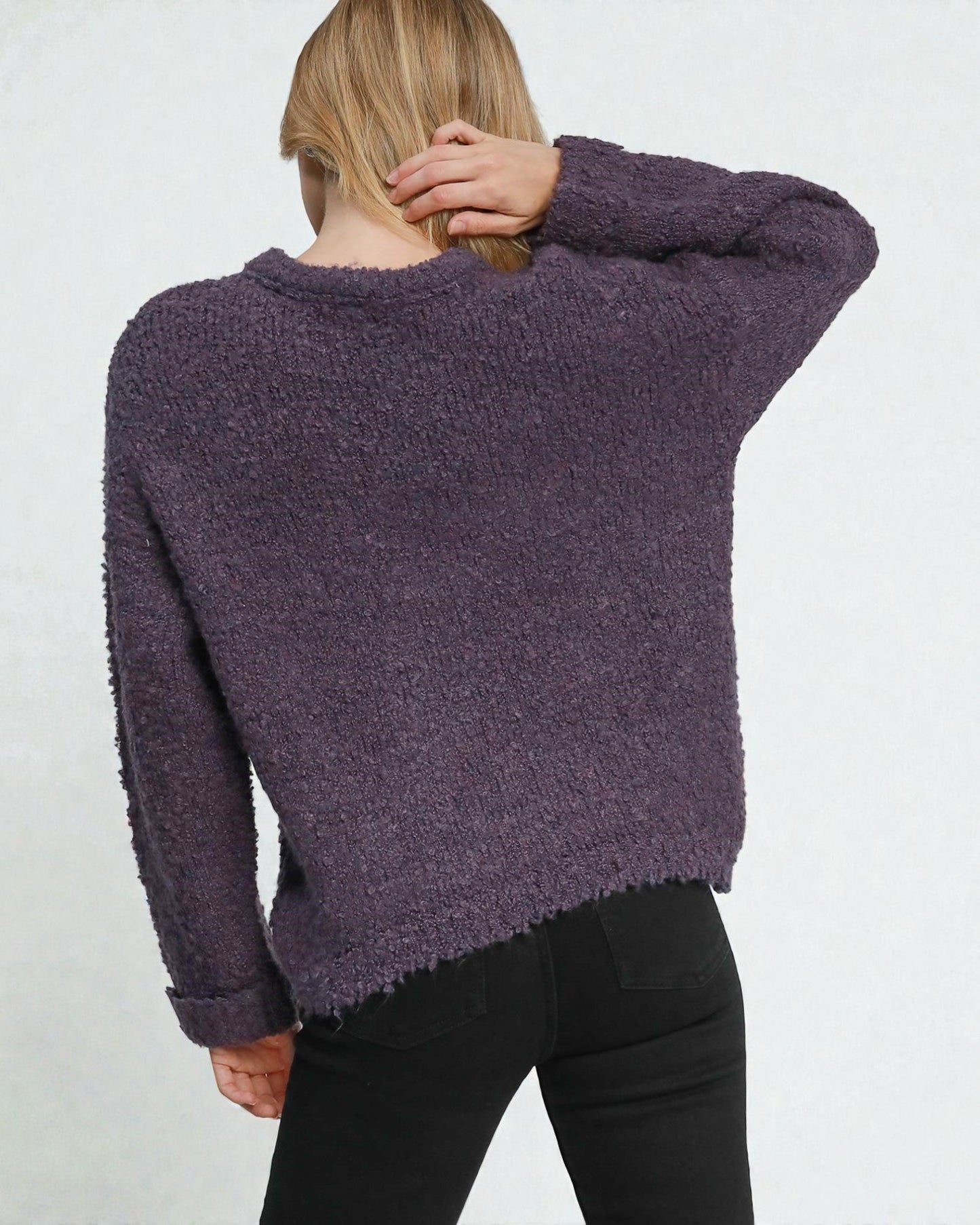 Person wearing a purple sweater with a plain background