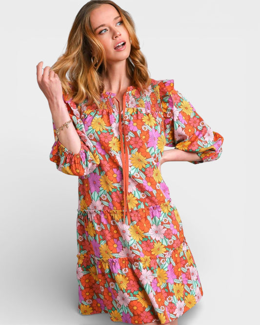 Woman wearing a colorful floral dress on a plain background