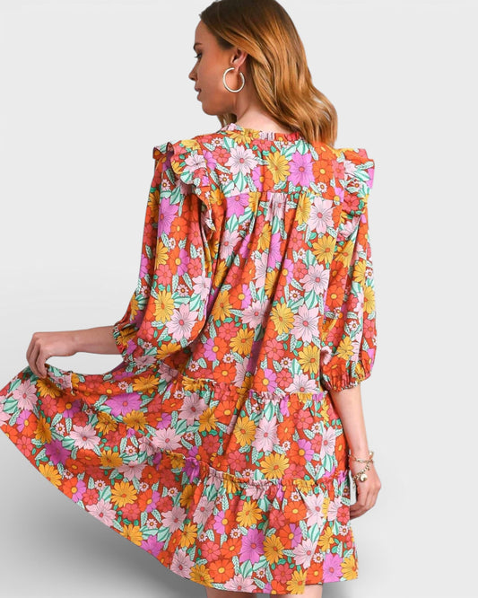 Woman wearing a colorful floral dress on a plain background