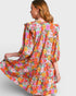 Woman wearing a colorful floral dress on a plain background