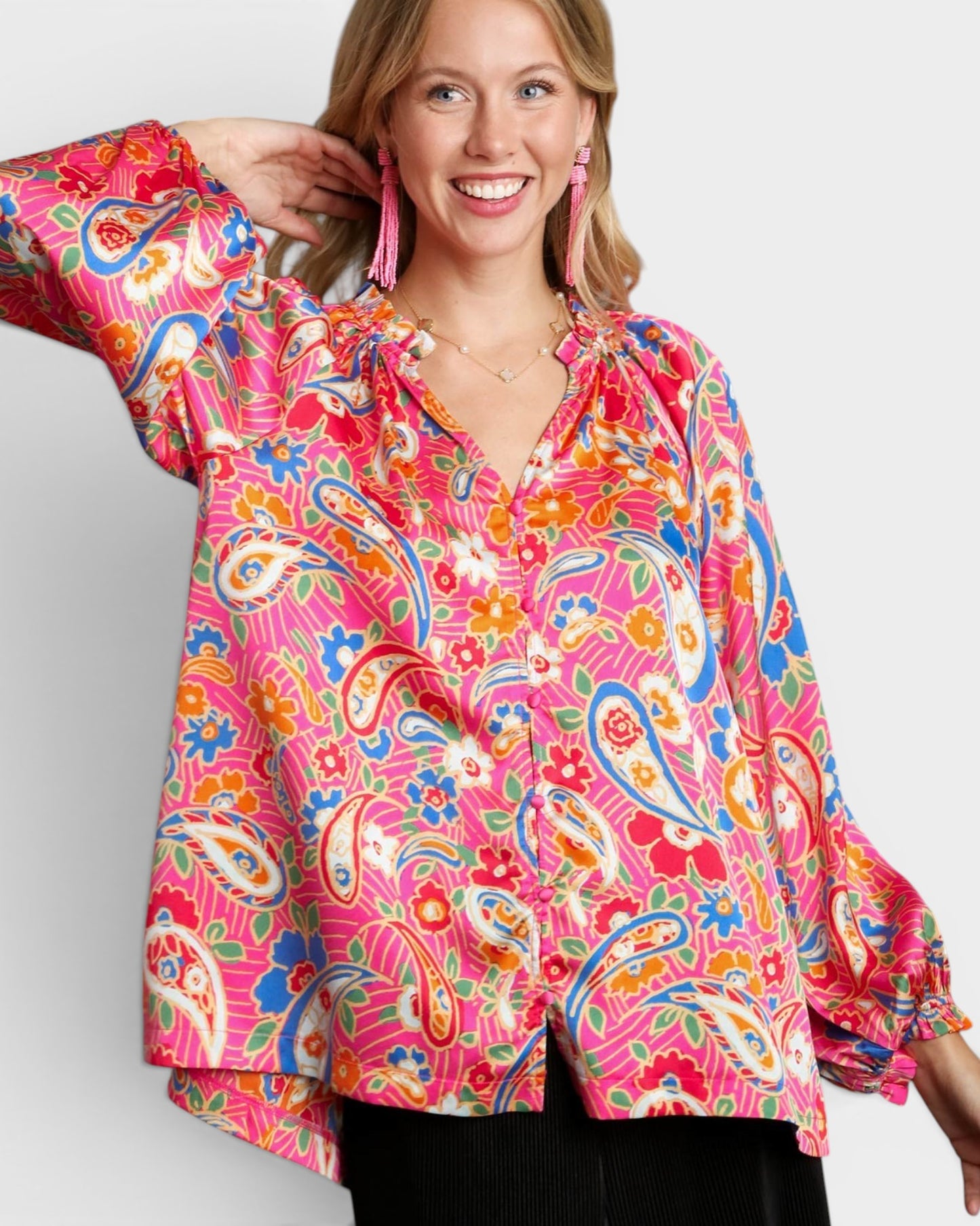 Woman wearing a colorful paisley blouse against a plain background