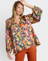 Woman wearing a colorful patterned blouse against a white background
