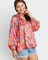 Woman wearing a colorful patterned blouse with denim shorts on a white background