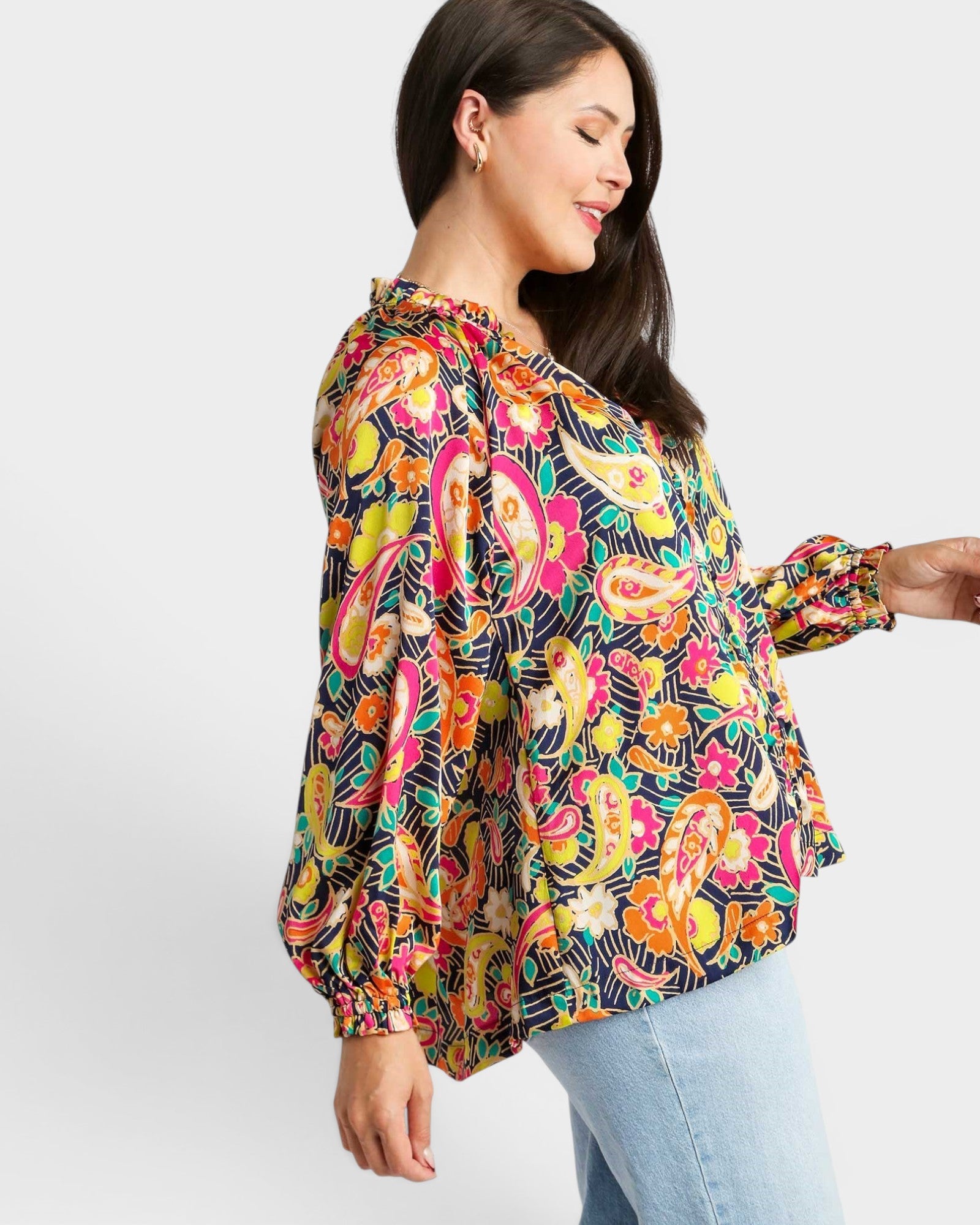 Woman wearing a colorful patterned blouse with a plain background