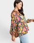 Woman wearing a colorful patterned blouse with a plain background